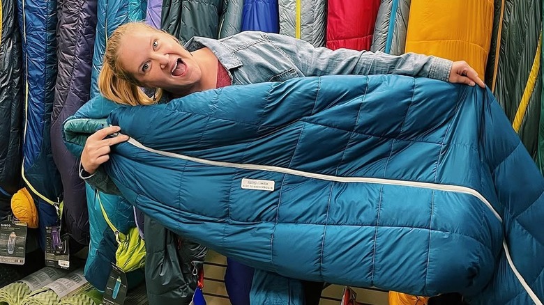 excited woman holding blue Sidewinder sleeping bag