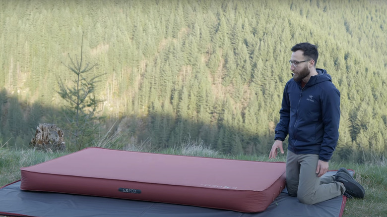 A man showcases the Exped MegaMat in the woods