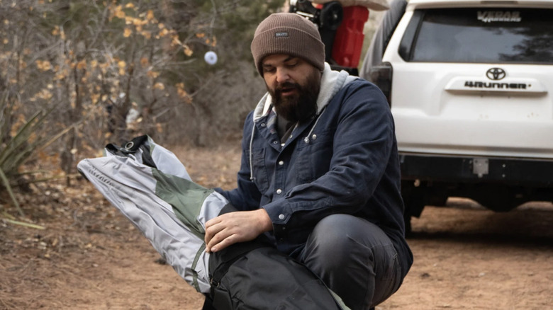 A man pulls a Gazelle tent from its carrying bag.