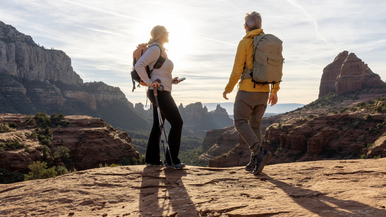 man and woman standing on a mountain plateau looking at other rock formations