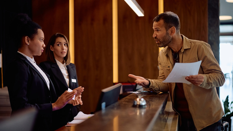 Angry guest discussing with managers while complaining about the bill after a hotel stay