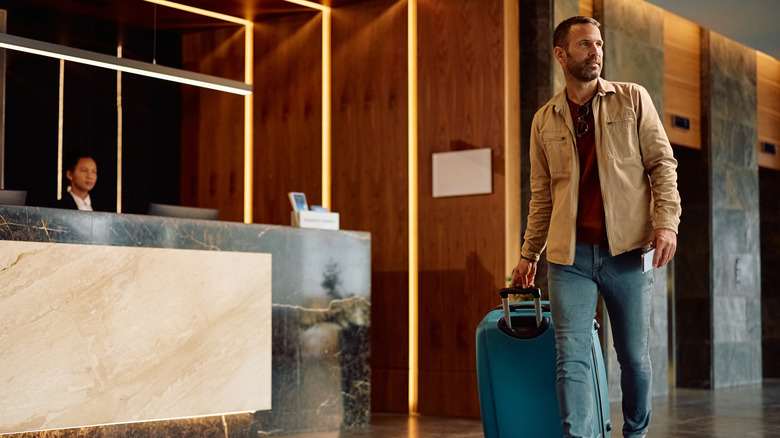 Hotel guest with travel bag walking through the lobby