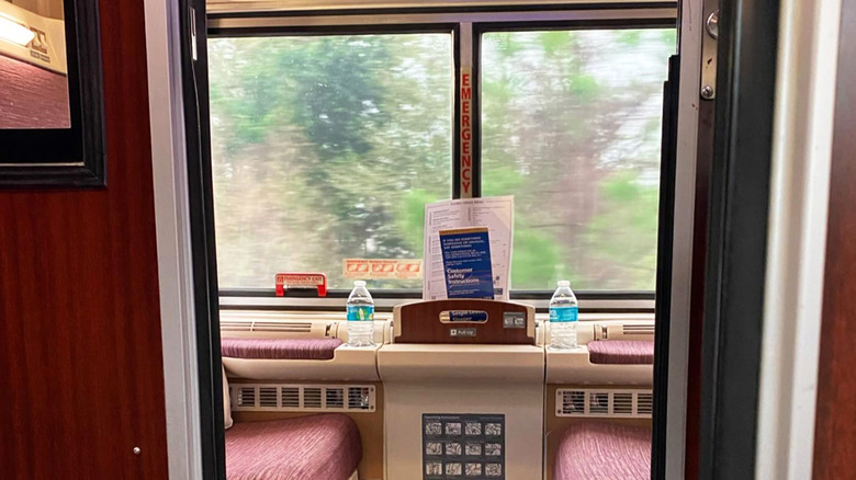 Amtrak roomette with two chairs and windows showing trees outside