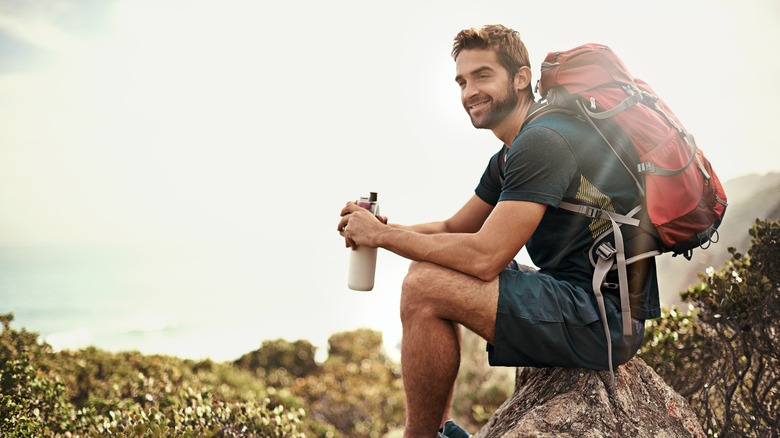 Guy sitting rock backpack water bottle