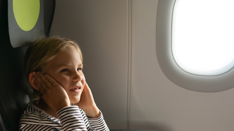 kid holding ears on plane