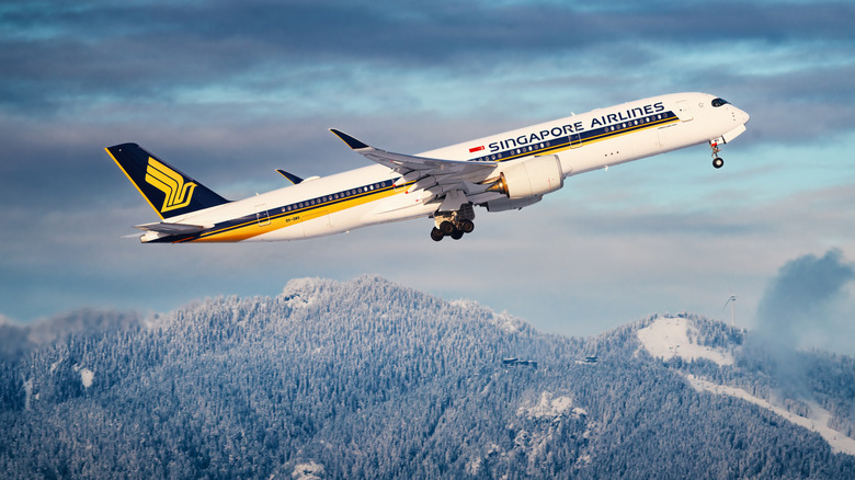 A Singapore Airlines passenger plane flies over snow-dusted mountains