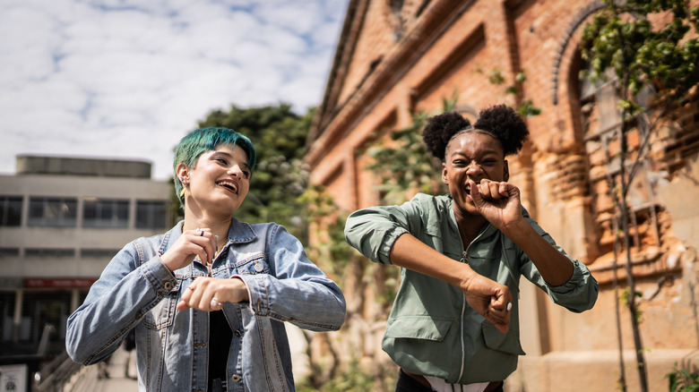 Two happy female friends having fun outdoors in summer vacations at city.