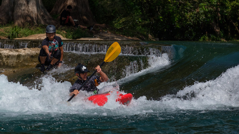 Whitewater kayakers enjoy the manmade features built into the flow of the San Marcos River at a city park in San Marcos, Texas.