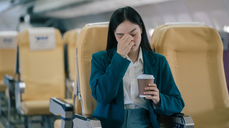 woman holding nose on flight