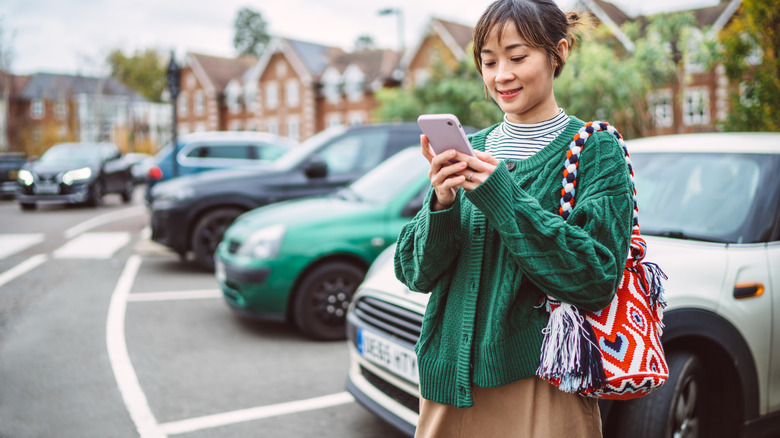 Traveler checking phone near parked car