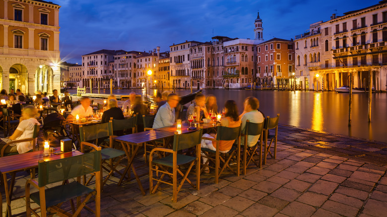 Diners at an outdoor restaurant along a canal in Italy