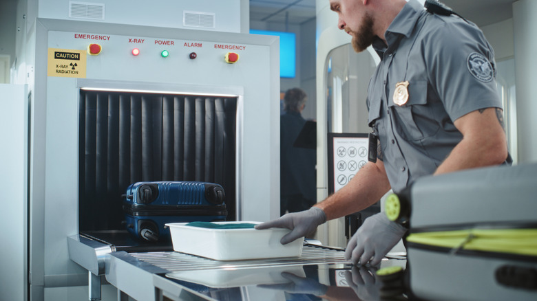 Airport security officer screening items through the scanner