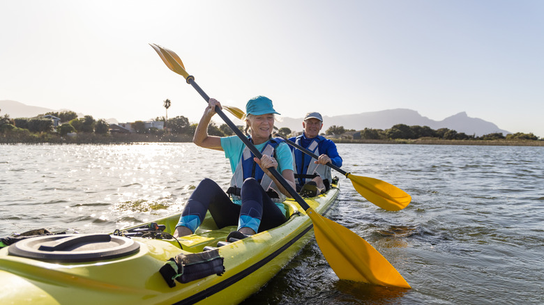 An older couple kayaking on a river.