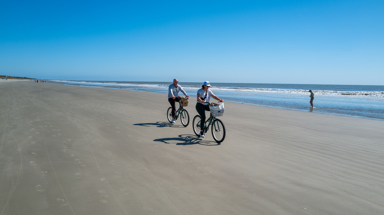 cyclists ride along a beach
