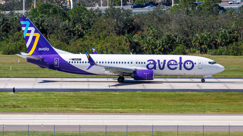A white and purple Avelo plane on a tarmac.