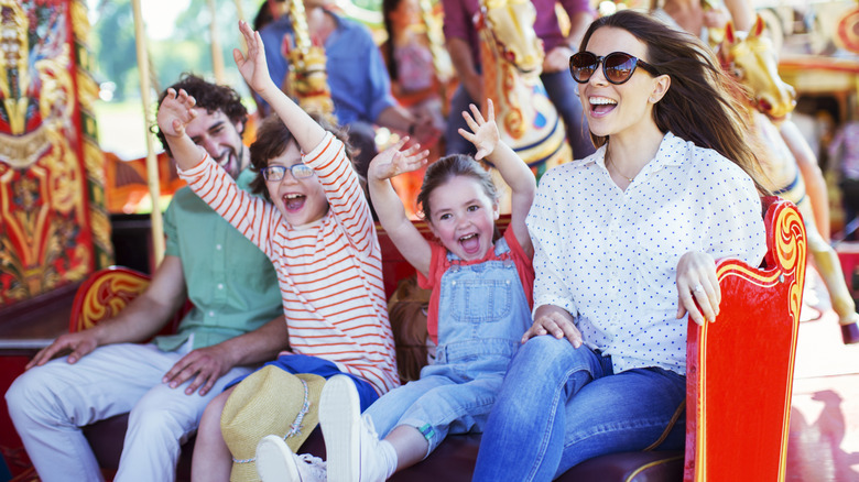 a family of four enjoying themselves on a ride at an amusement park