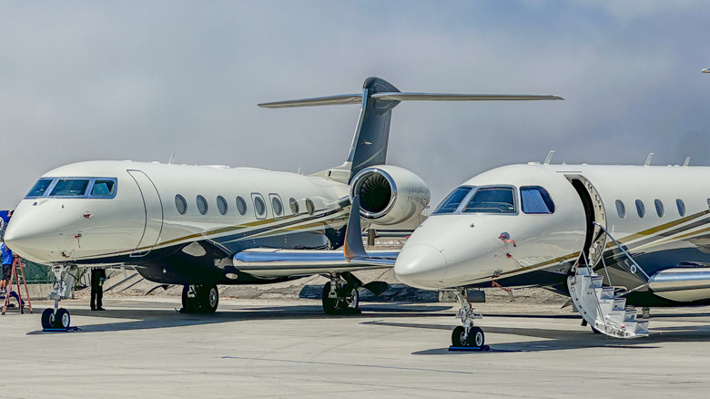 Two white and gold private jets parked on the runway