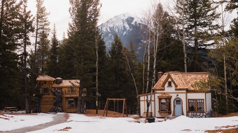A scenic snowcapped mountain in the background with 2 cottages in foreground with snow on the ground