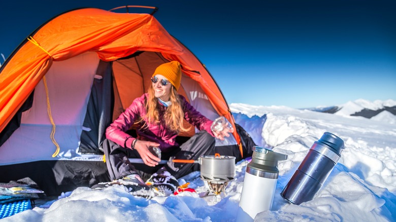 Woman sitting outside of a tent in the snowy mountains