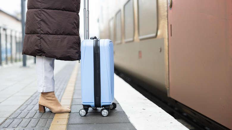 stylish boots and suitcase at train