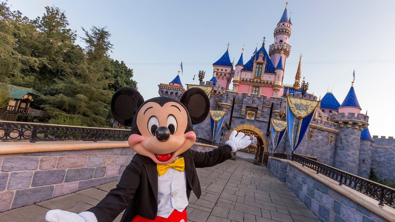 Mickey Mouse poses in front of Sleeping Beauty's Castle at Disneyland Park