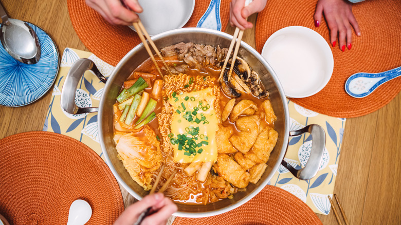 People sharing a large hotpot bowl with chopsticks