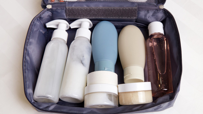 A toiletry bag is open on a flat surface, showcasing neatly arranged bottles of shampoo