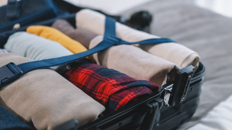Neatly packed suitcase filled with rolled up clothes.