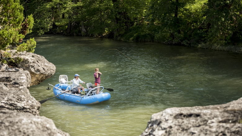 people fishing in dinghy on river