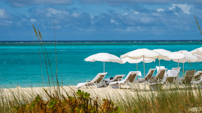 Beach loungers and white umbrellas line the soft sandy shores of Grace Bay in Providenciales, Turks and Caicos