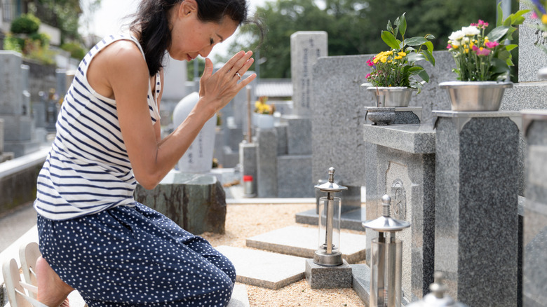 A woman prays before a grave site in Japan