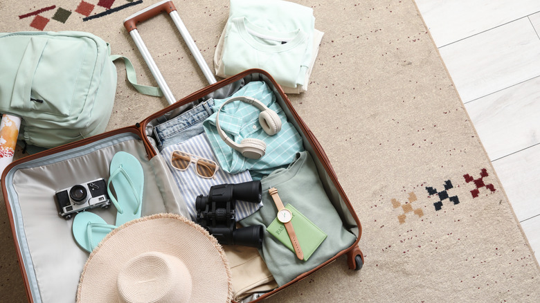 Clothes and other items are half-packed into an open suitcase