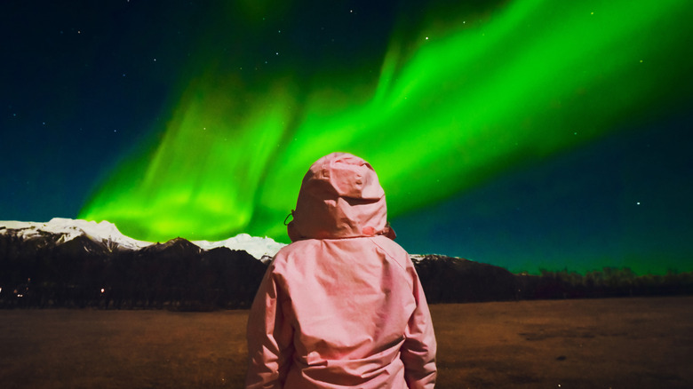 Woman in a pink jacket looking at the Northern Lights in Iceland