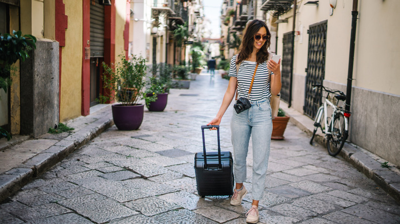 Woman looking for directions on cellphone, while walking through Italian village