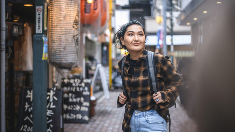 Relaxed young Mongolian woman pausing to look and fully appreciate the beautiful vibrancy of Tokyo at dusk.