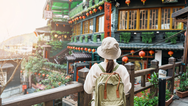 Female tourist with hat and backpack sightseeing in Jiufen Old Street village in Taiwan