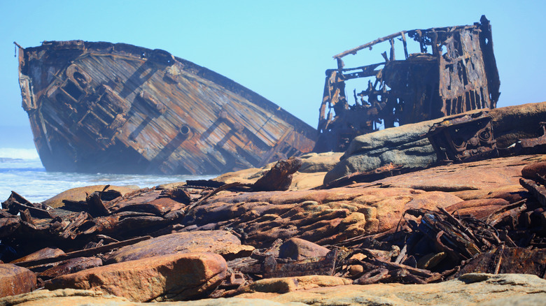 Rusty remains of a ship wreck in the fore ground with the bow section clearly visible on the Skeleton coast, Namibia