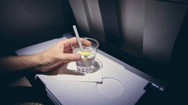 Hand holding drink on plane tray