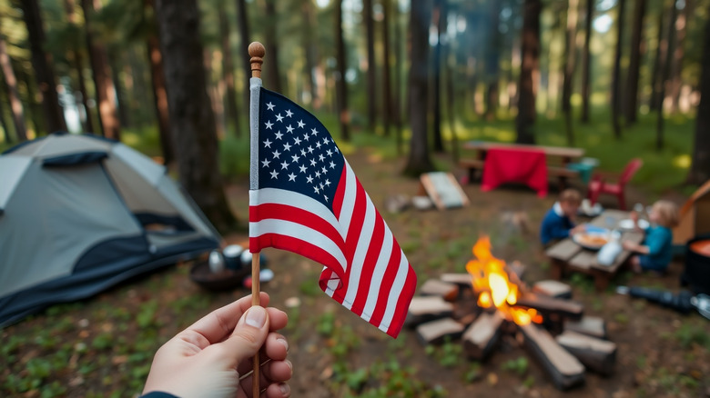 Hand holding American flag at campsite