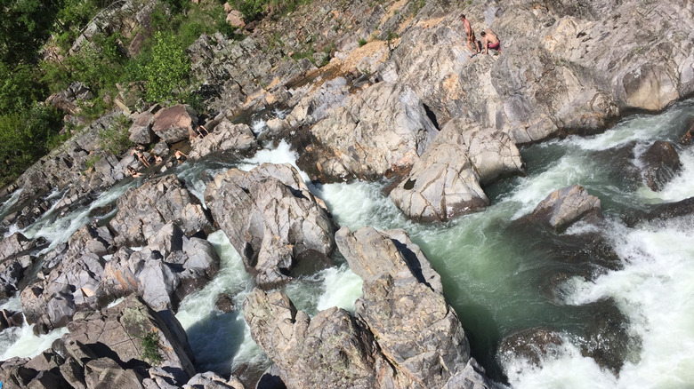 People playing among rocks by gushing river
