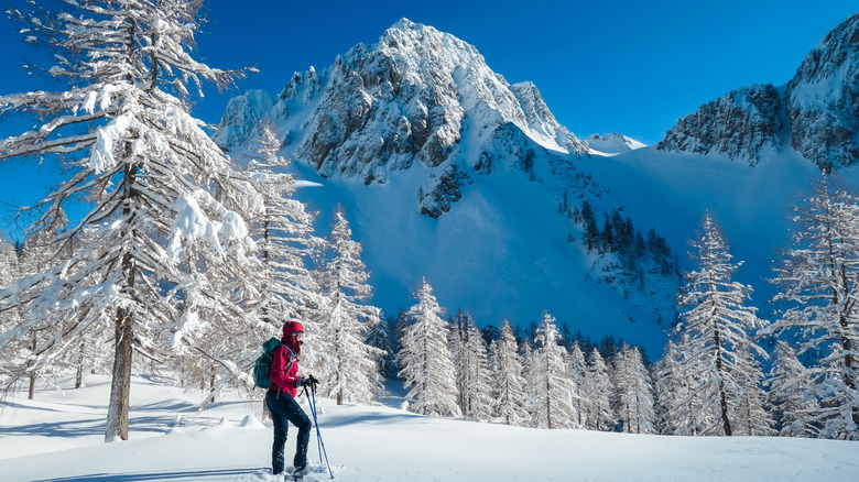 Woman walking in snow shoes with panoramic view of snow capped mountain peak in Austria