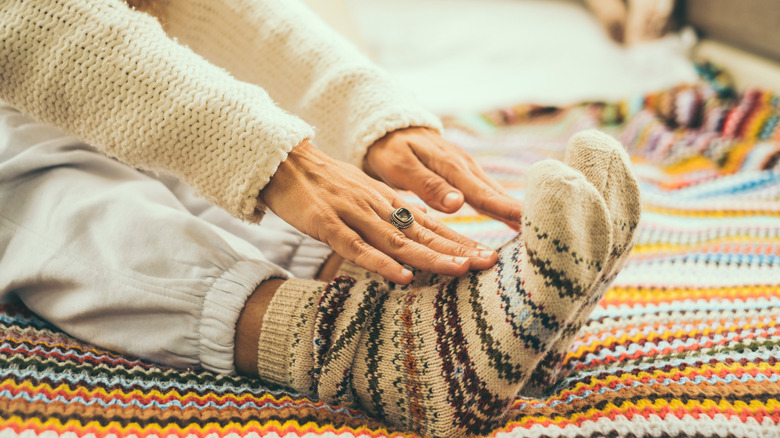 Close up of woman doing stretching exercises on the bed wearing colorful winter warm wool socks.