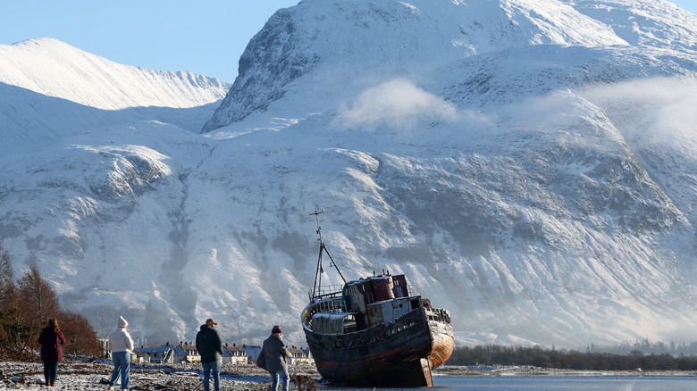 People view a former fishing boat on the shore of Loch Linnhe in front of Ben Nevis in Corpach, United Kingdom.