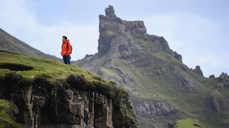 A hiker standing on a cliff in The Quiraing, Isle of Skye