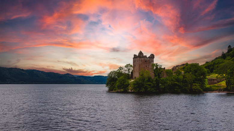 Urquhart Castle and the mysterious Loch Ness in the fiery light of sunset in Scotland