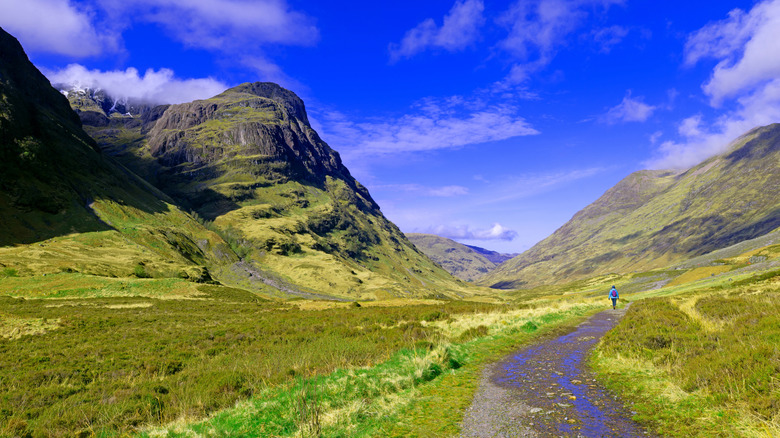 Long shot of a hiker walking through the lost valley in Glen Coe, Scotland