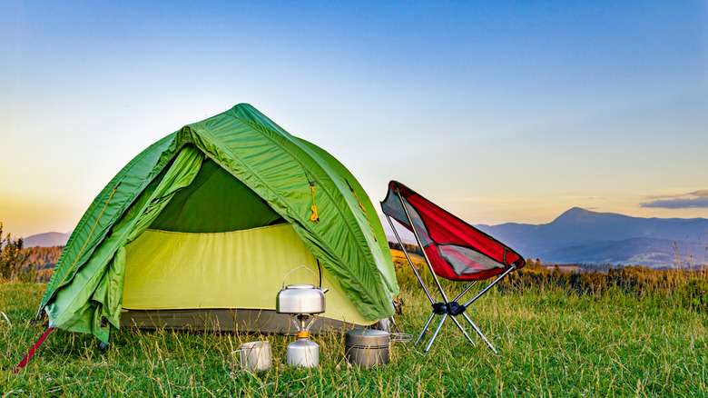 Green tent setup outside with camping equipment