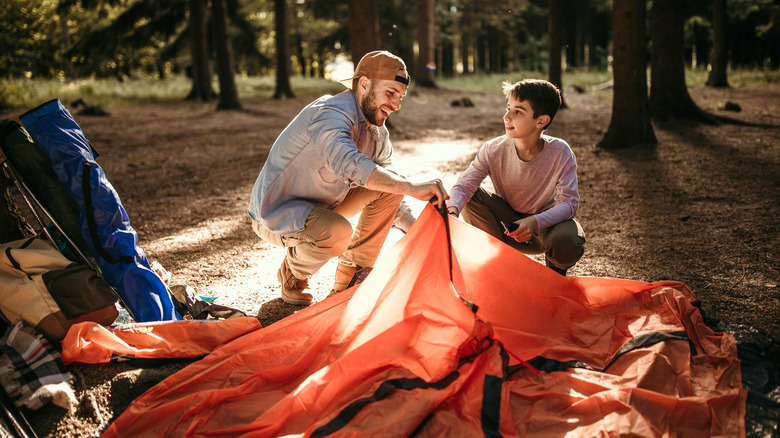 father and son setting up tent