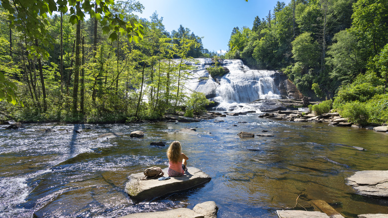 Woman sitting on rock looking at High Falls in DuPont State Recreational Forest