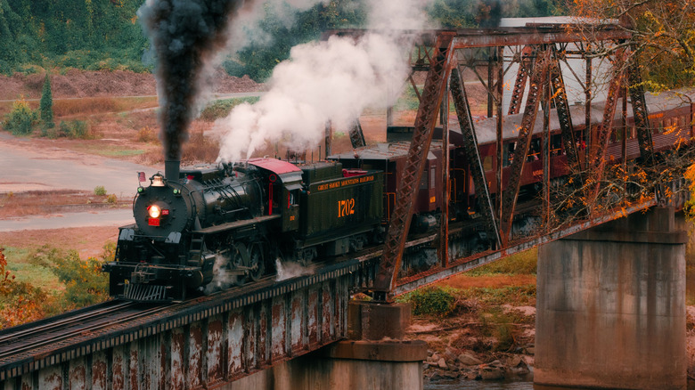 Steam train crossing bridge on Great Smoky Mountain Railway in fall